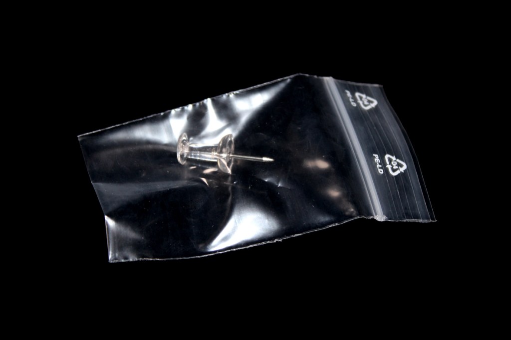 A picture of a push pin, individually bagged.