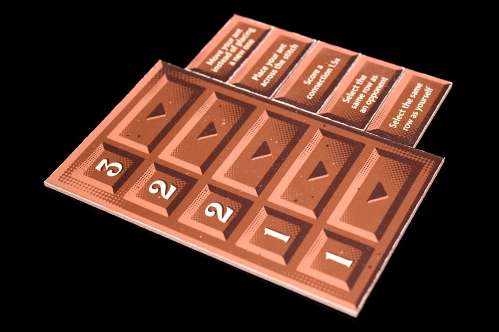 Close-up of a game board displaying chocolate bar pieces and scoring instructions.