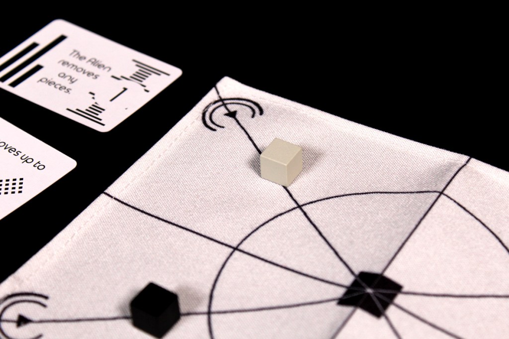 Close-up of a game board showing rules and components including black and white pieces, with a visual grid and markings for gameplay.