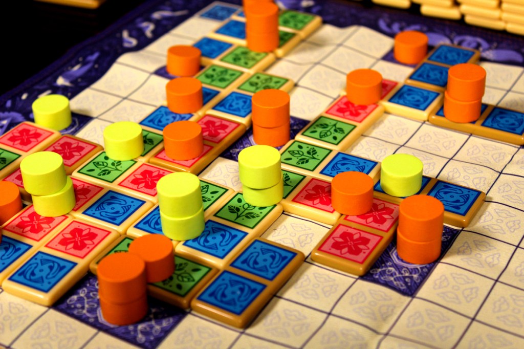 Game board featuring various colored domino pieces and player tokens arranged in a strategic pattern.