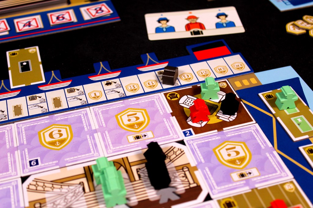 A close-up view of a board game setup for 'Come Sail Away!', featuring various player pieces, game tiles, and player boards displayed on a black surface.