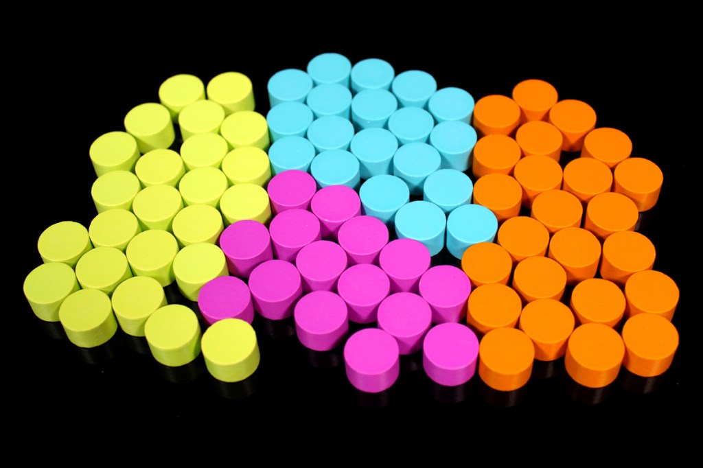 Colorful game tokens in various shapes arranged in a patterned layout.