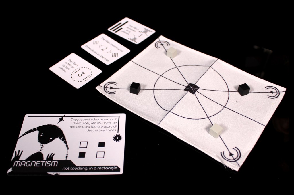 A game setup featuring a play mat with a central design and tokens, alongside role cards that explain game mechanics.
