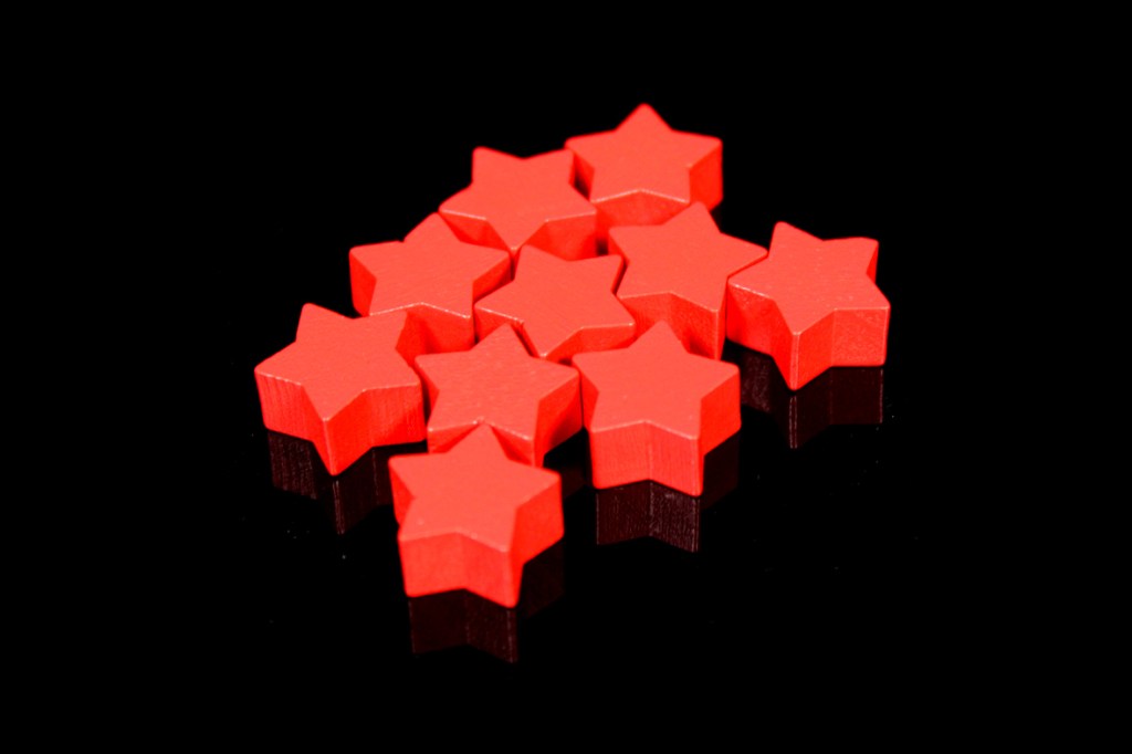 A collection of red star-shaped game tokens arranged on a black surface.
