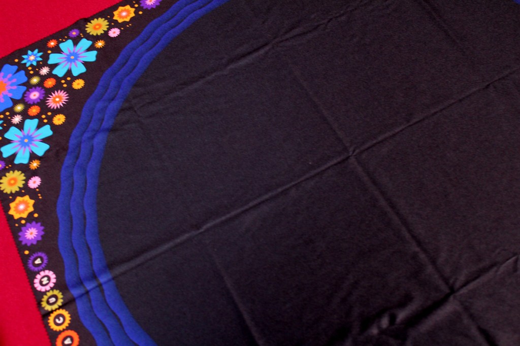 A colorful game mat featuring floral designs on the edges, with a dark background.