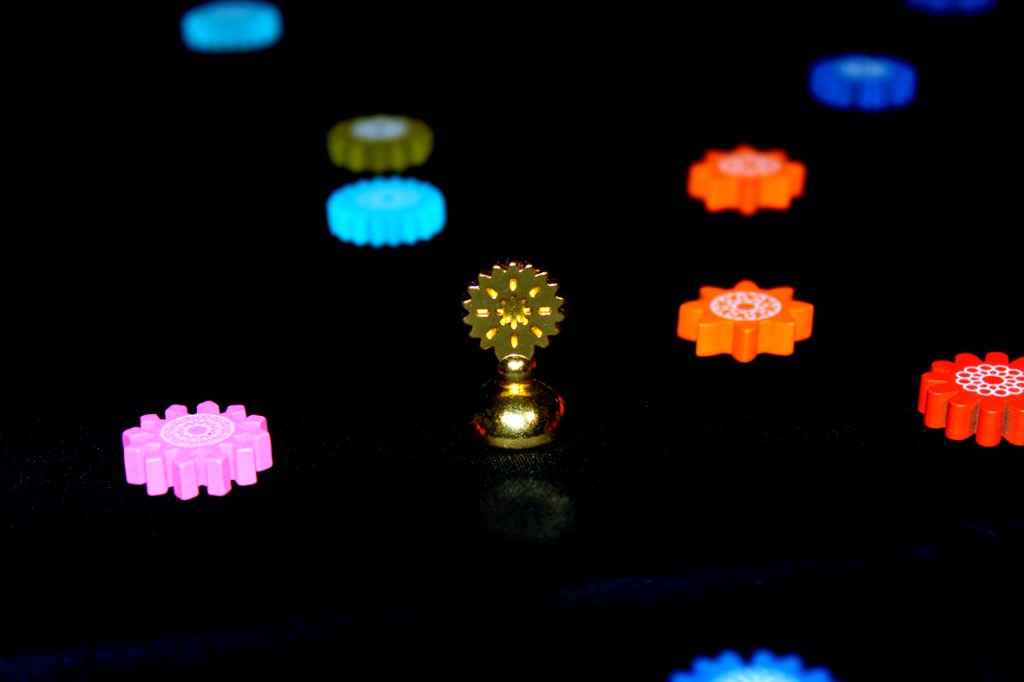 A golden pawn surrounded by colorful flower tokens on a black background.