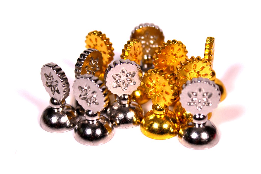 An assortment of metal game pieces in silver and gold, featuring distinct decorative designs and varying heights.