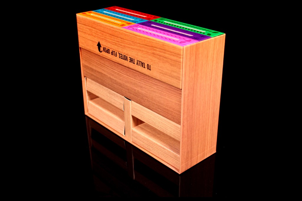 A game box designed for the board game 'Survivor: The Tribe Has Spoken', featuring vibrant colored voting slots on top and drawers for storage.