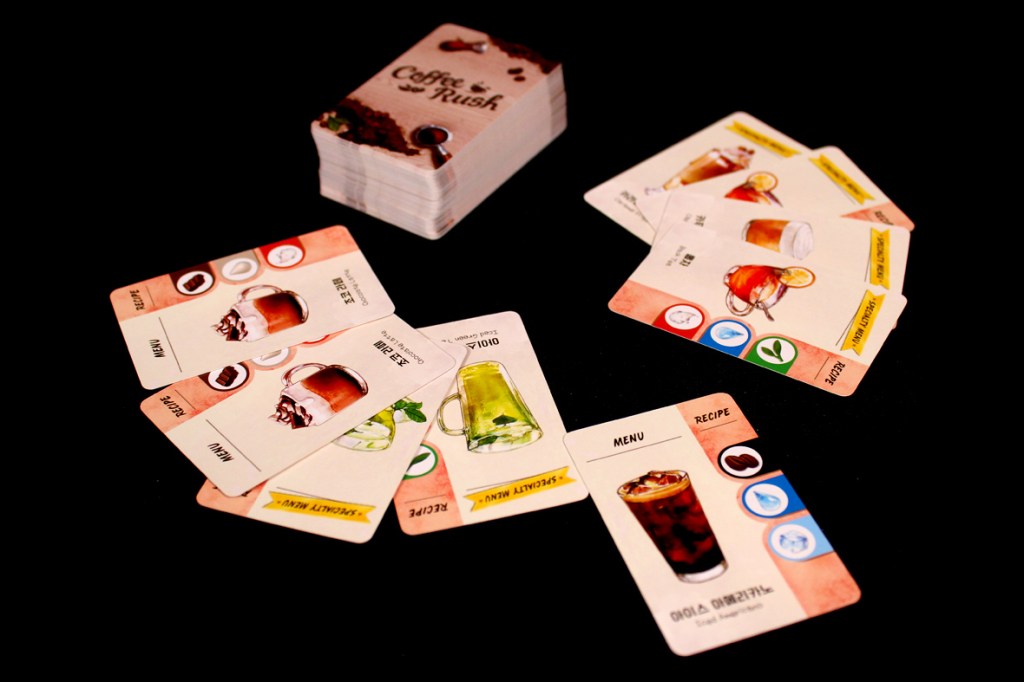 A selection of cards from the board game Coffee Rush, showing various drink recipes and menus, with a stack of cards in the background.