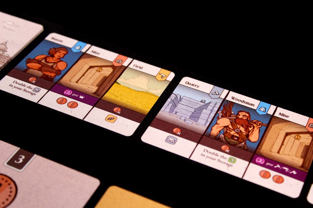 Game cards from the board game Ancient Realm showing various buildings and resources.
