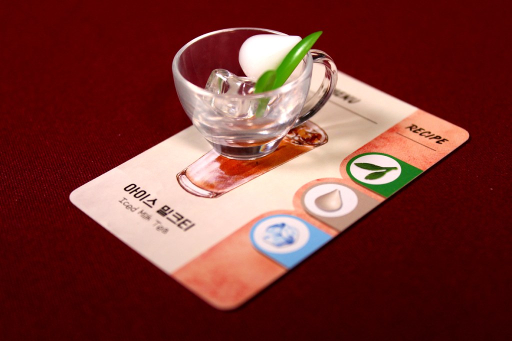 A clear glass cup with ice and a green garnish sits on a recipe card labeled 'Iced Mint Tea' in Korean and English.
