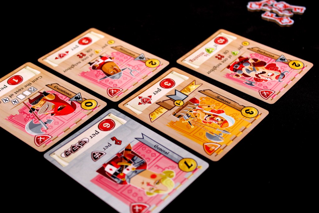 A close-up of several colorful cards from the board game Castle Combo, displaying various character illustrations and game mechanics.