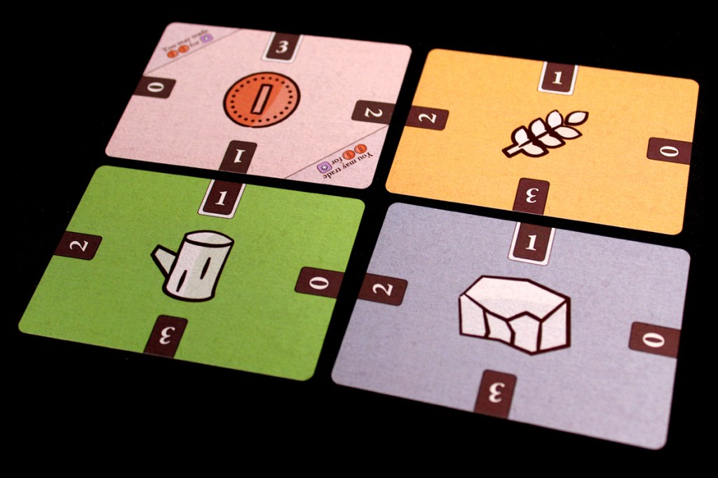 Four resource cards representing different types of commodities in a board game, each displaying various quantities and values.