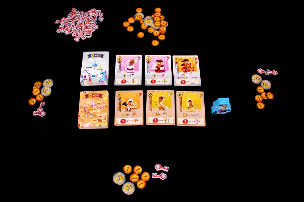Game setup for Castle Combo featuring cards, coins, keys, and tokens on a black surface.