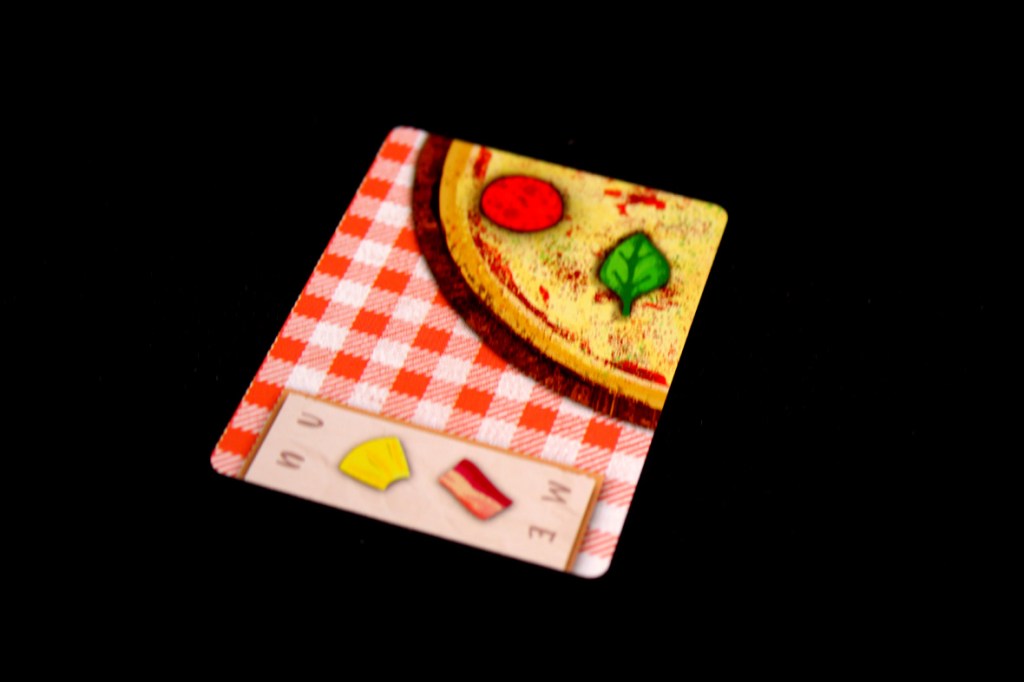 A close-up image of a pizza card from the game Pizza Pizza Yum Yum, featuring toppings such as pepperoni and basil on a checkered background.