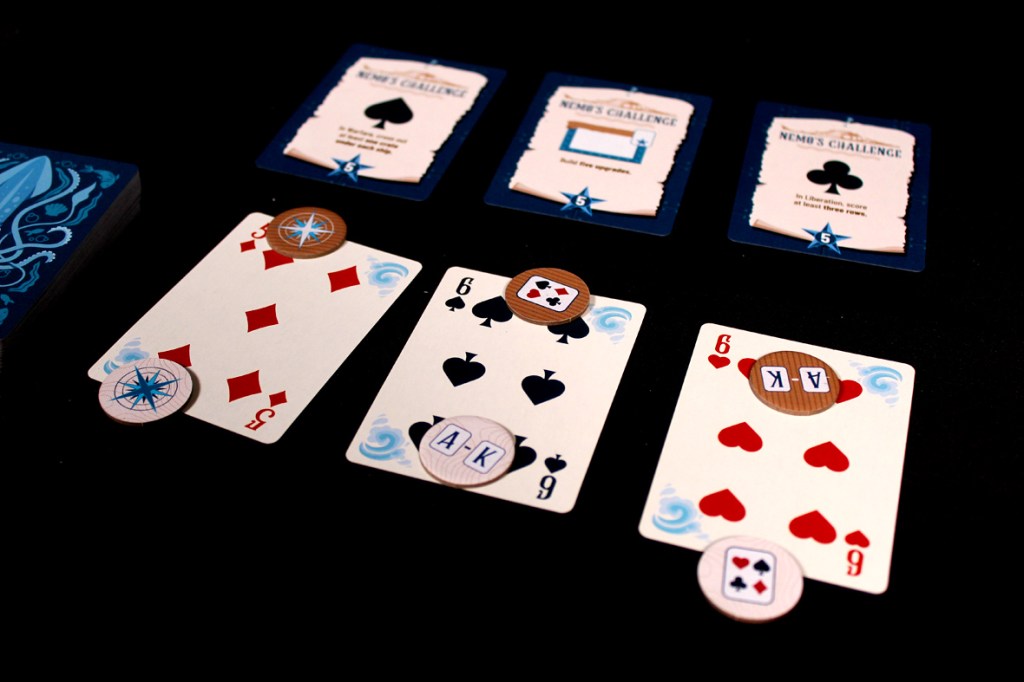 An assortment of playing cards and challenge cards from the board game Flip Voyage, featuring various suit ranks and symbols against a dark background.