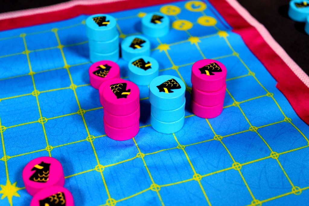 Colorful game pieces arranged on a blue game board, featuring yellow grid lines and pink and blue tokens.