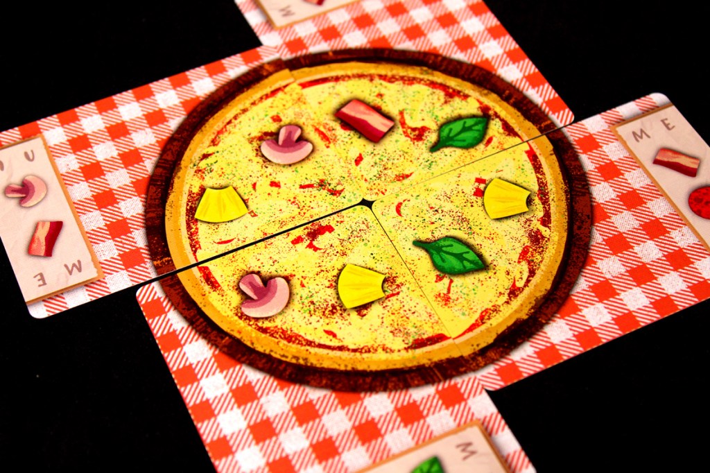 A board game layout featuring a pizza divided into four slices, topped with various ingredients like mushrooms, peppers, and herbs, on a red checkered tablecloth.