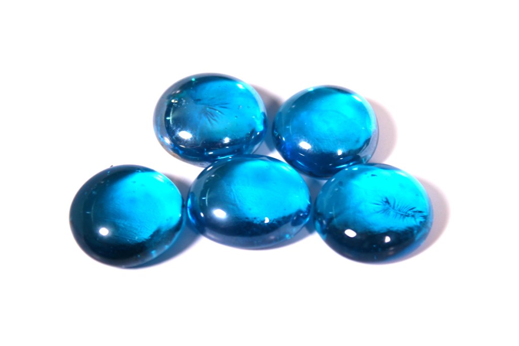 Five blue glass gems arranged in a triangular formation, reflecting light.