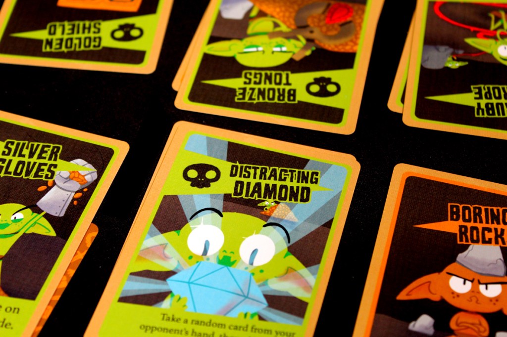 Close-up view of cards from the game 'Squabblin Goblins,' featuring colorful illustrations of goblins and items like the 'Distracting Diamond' and 'Silver Gloves.'