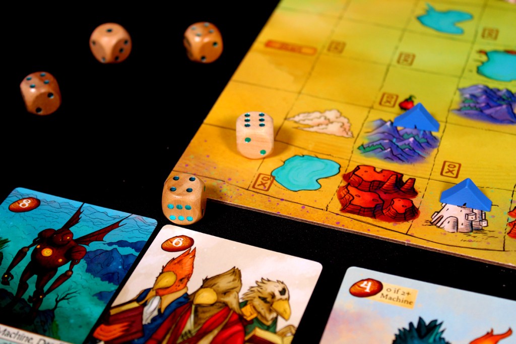 A tabletop game in progress featuring a colorful game board with distinct terrains and game pieces, along with wooden dice and character cards displayed in the foreground.
