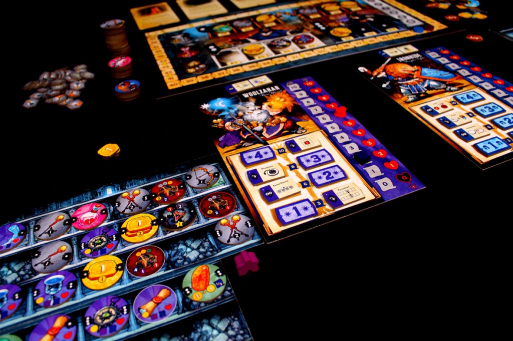 Close-up of a board game setup featuring character boards, tokens, and game pieces on a black background.