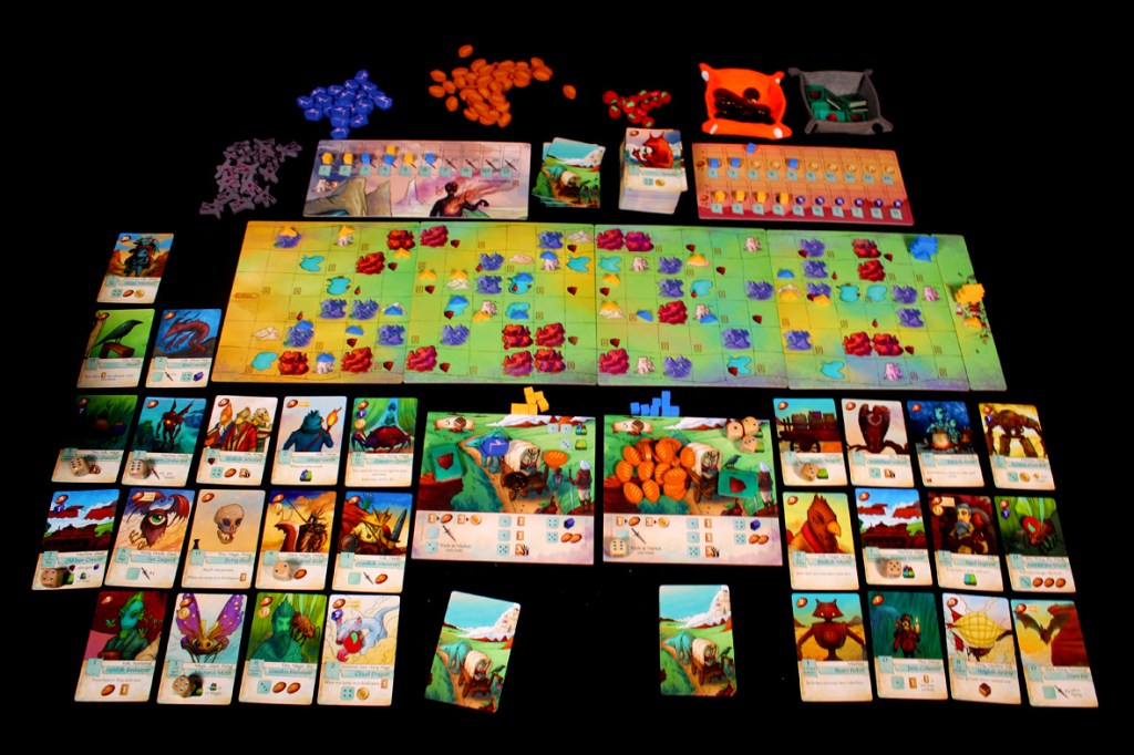 A bird's eye view of a game board for Creature Caravan, displaying various game pieces, including cards, tokens, and a colorful modular landscape.