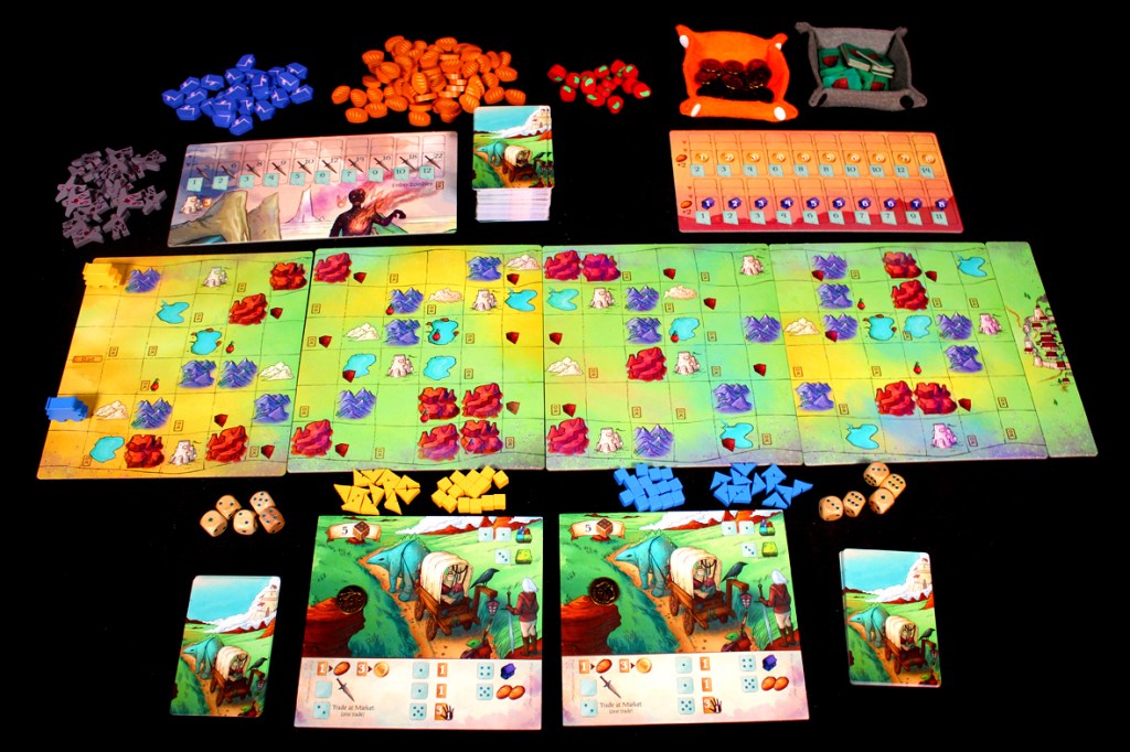 A colorful board game setup for 'Creature Caravan', featuring game boards, cards, various player pieces in multiple colors, dice, and tokens arranged on a black surface.