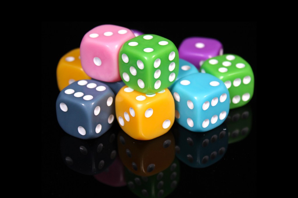 A colorful array of various dice stacked together on a reflective surface.