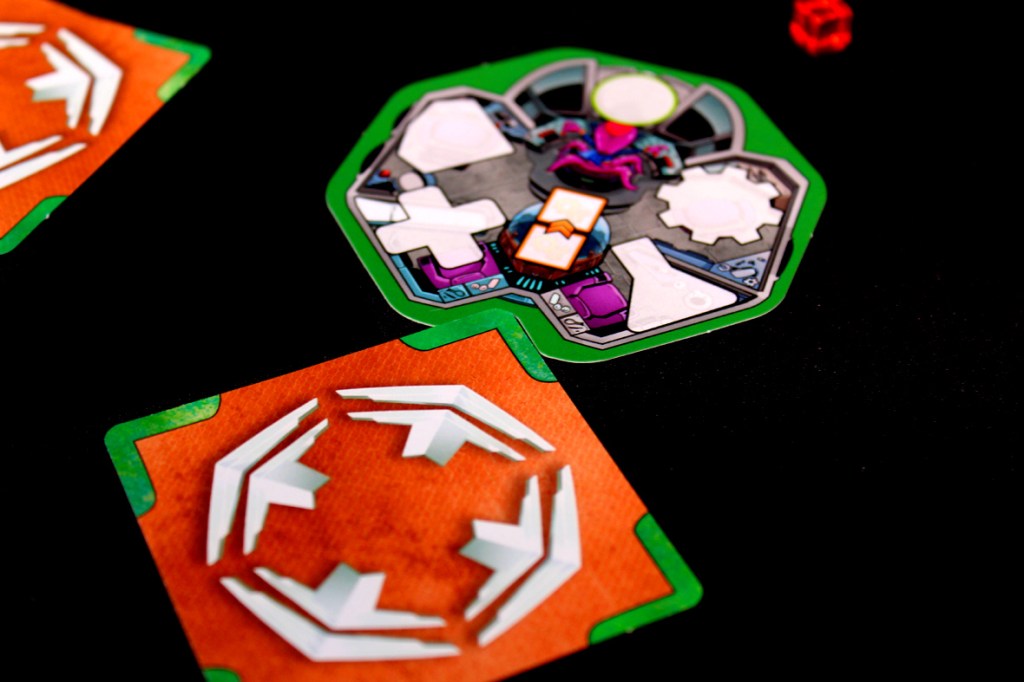 Close-up of game tiles for 'Crash & Grab', featuring a character and directional markers, set against a black background.