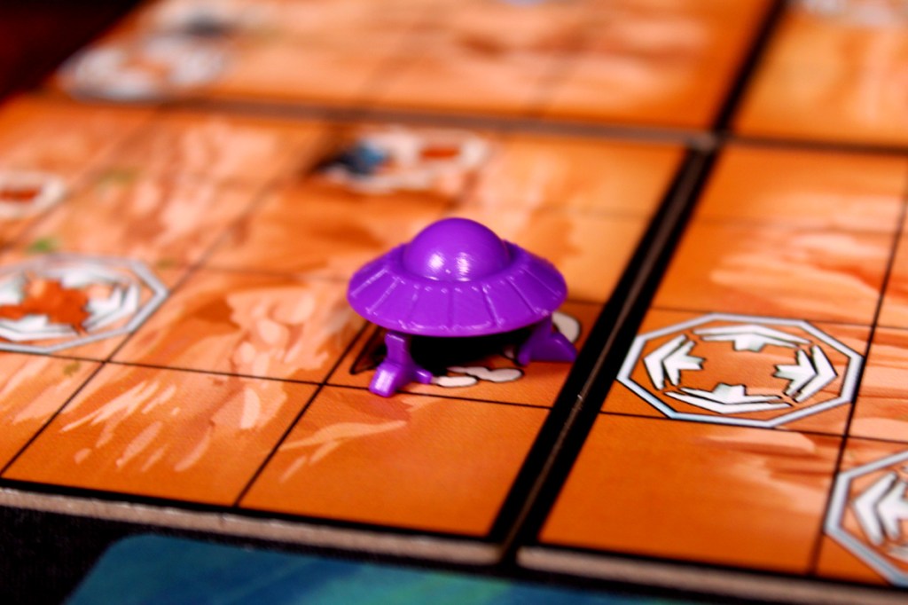 A purple saucer token on an orange game board, showcasing various movement indicators and terrain features.