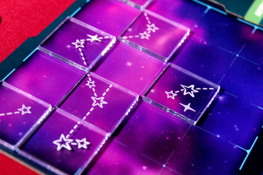 An array of transparent game tiles arranged on a colorful night sky background, depicting stars connected by dashed lines, showcasing a star charting theme.