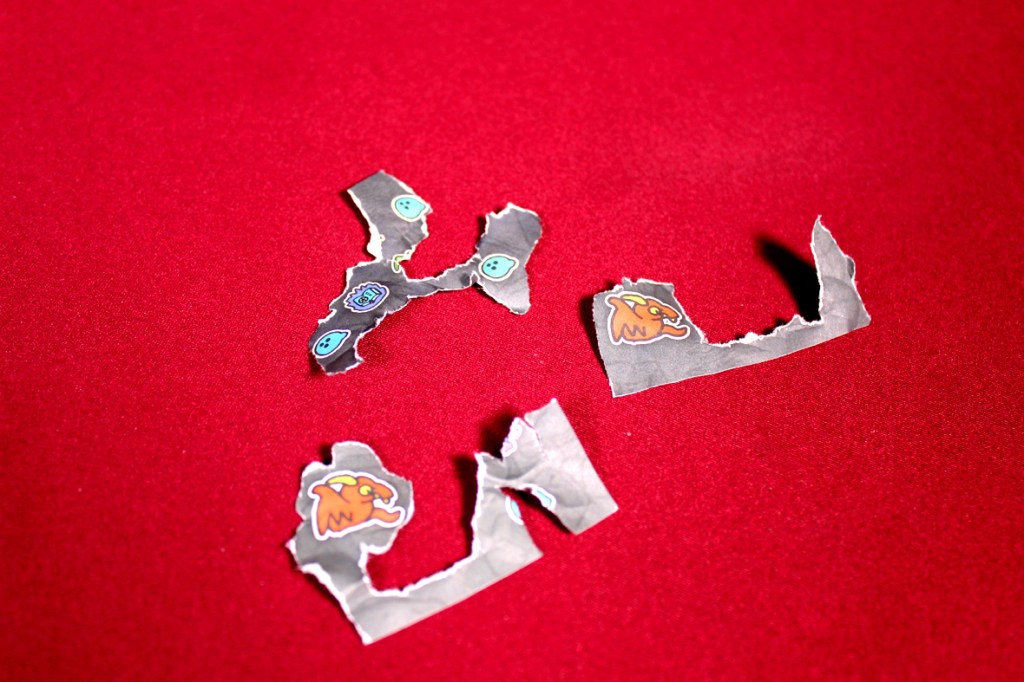 Torn pieces of paper with colorful monster illustrations scattered on a red background.