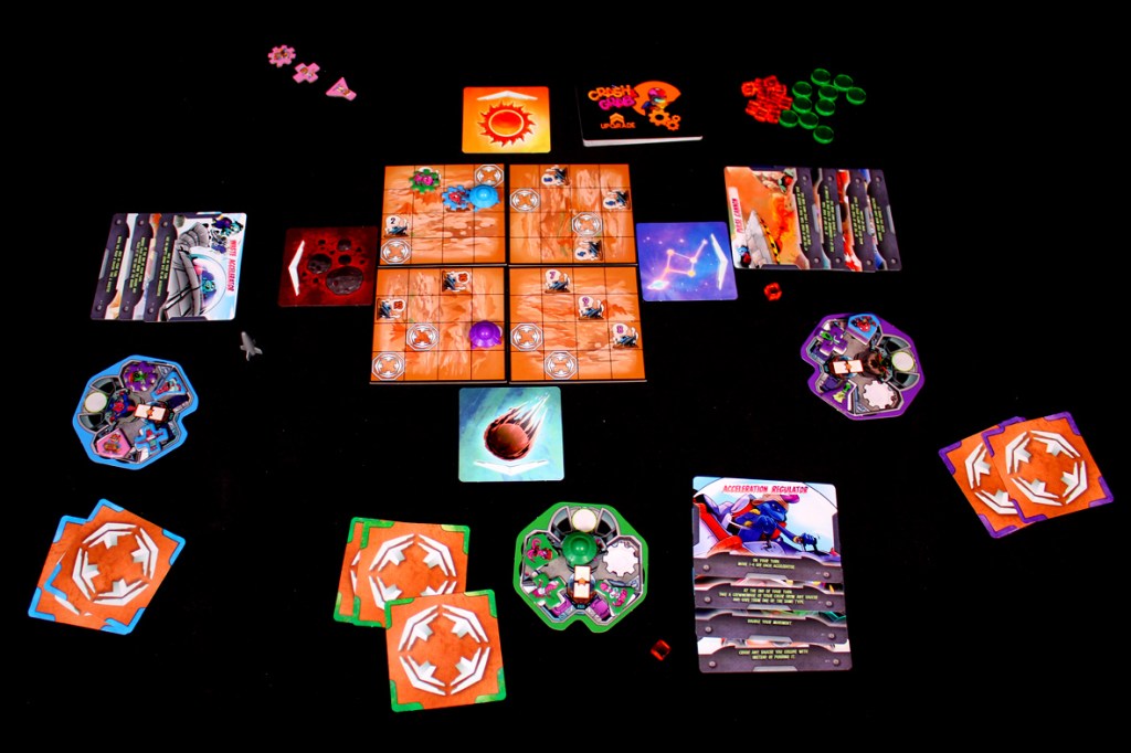 A tabletop game setup for 'Crash & Grab' featuring a central board with movement tiles, player tokens, energy markers, and cards, surrounded by game components on a black background.