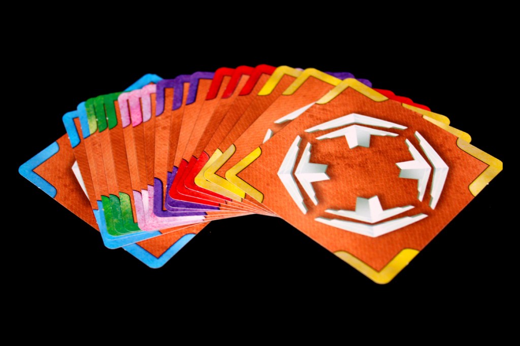 A fanned arrangement of colorful movement cards from the board game Crash & Grab, featuring various directional arrows and a vibrant color palette.