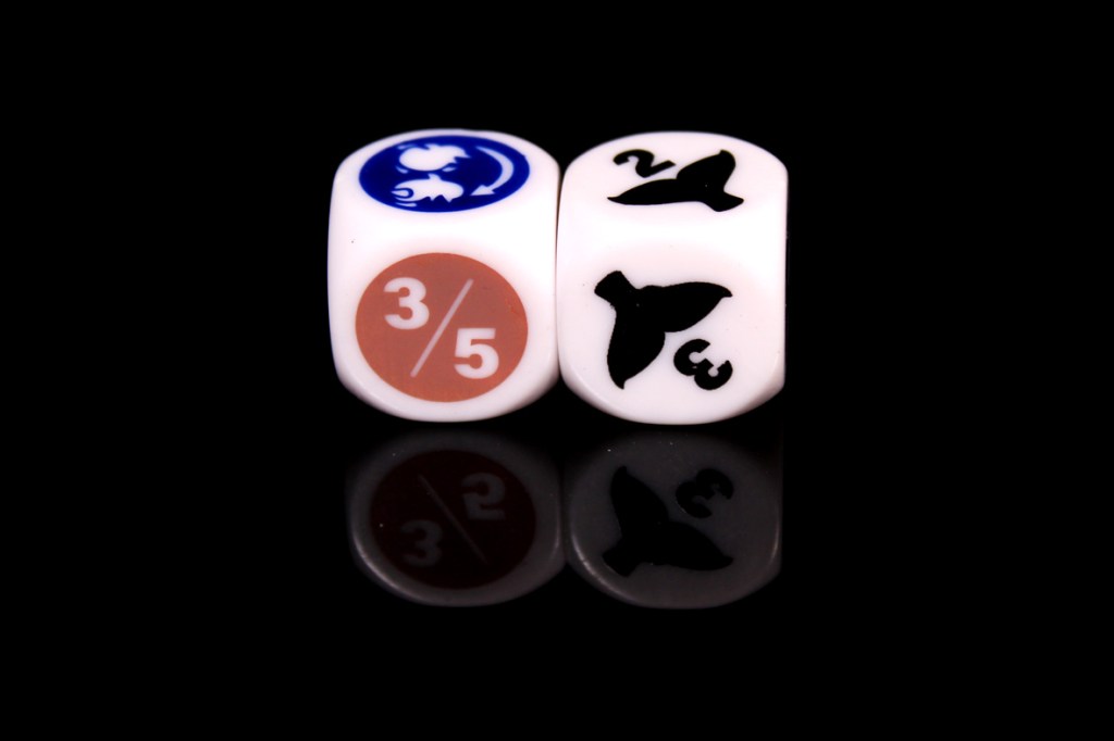 Two dice with various symbols and numbers displayed, resting on a reflective surface.