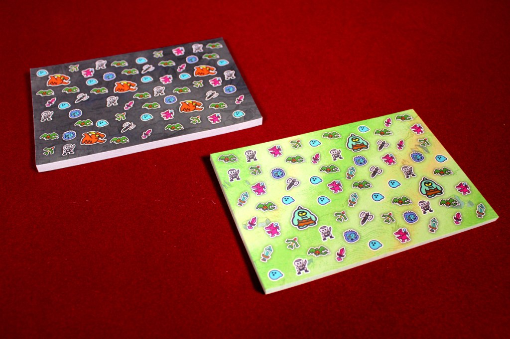 Two game player sheets for Tearable Quest featuring colorful illustrations of monsters and items, set against a red background.