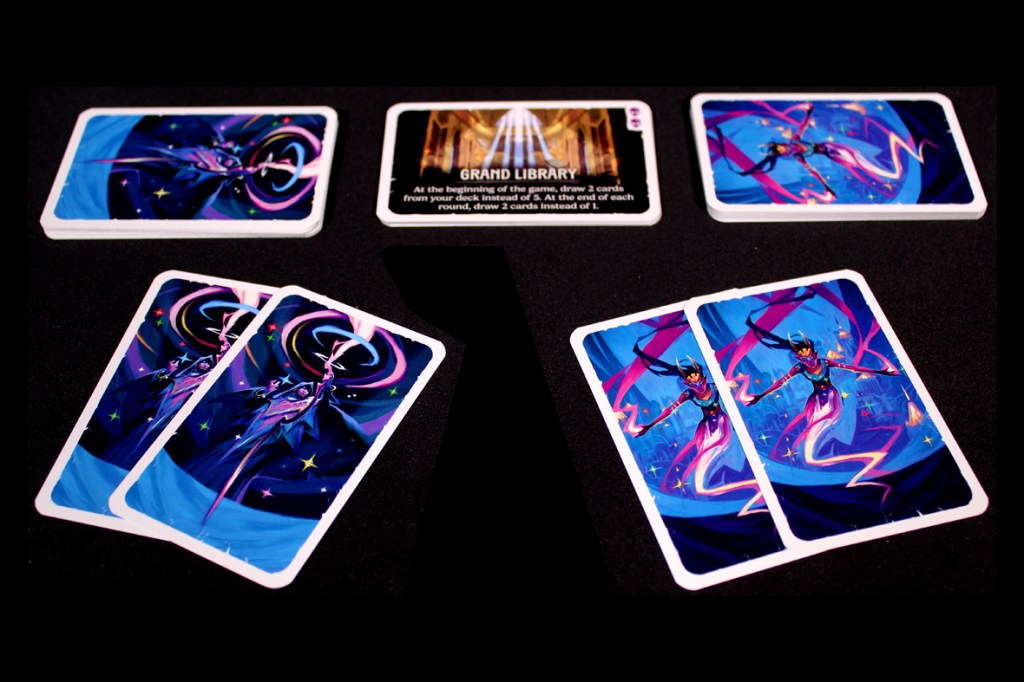 An array of card game components featuring two sets of illustrated character cards and a location card titled 'Grand Library' with game instructions.
