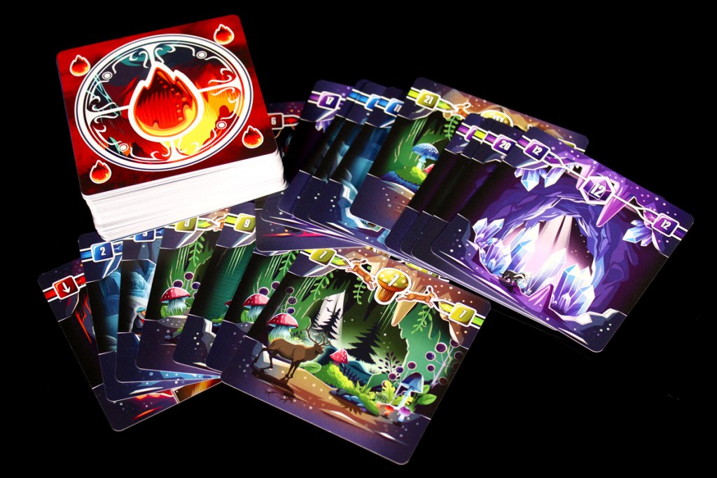 A stack of gaming cards featuring vibrant artwork, including an elemental fire symbol and various mystical landscapes with mushrooms, trees, and crystalline caves.