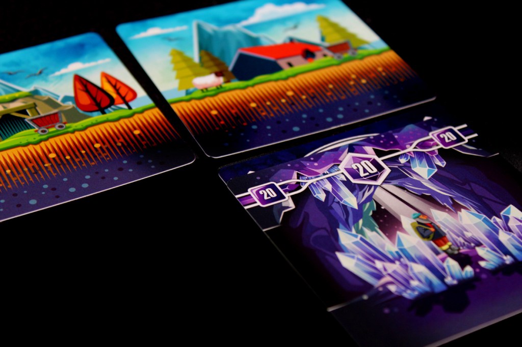 Three game cards from Tranquility: The Descent featuring a colorful landscape with a farm, trees, and a cave entrance adorned with crystals.