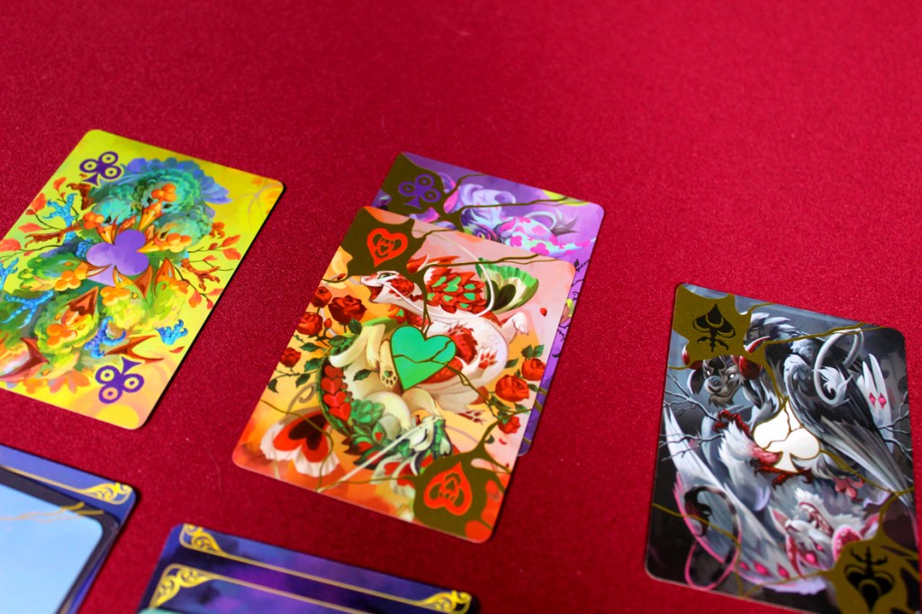 Colorful playing cards featuring intricate designs and animal illustrations on a red table.