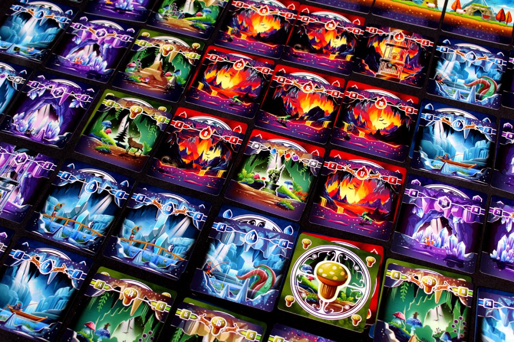 A close-up view of colorful game cards arranged in a grid pattern, featuring various mystical and cave-themed illustrations, each with different numerical values.