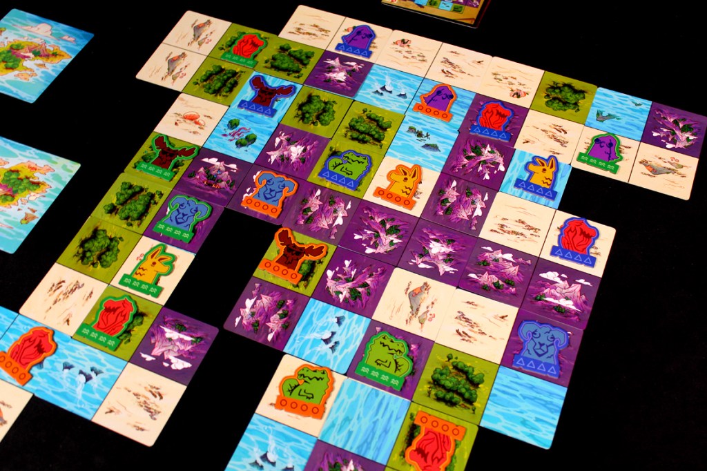 A colorful board layout from the game Oddland, featuring various landscape tiles and tokens representing strange animals and territories.