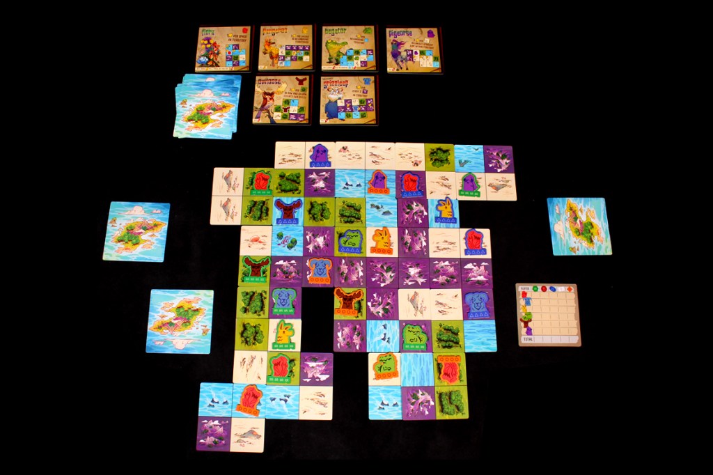 A colorful board game layout featuring various animal tokens and landscape cards on a dark background, with scoring cards visible at the top.