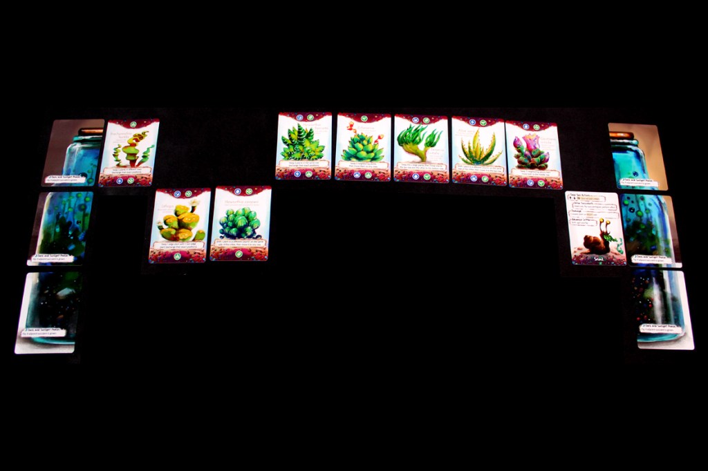 An arrangement of plant and bottle cards laid out on a dark table, showcasing various types of plants and their respective nutrient indicators in a game setting.