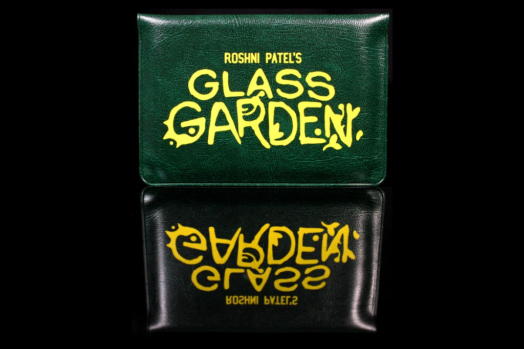 Green wallet featuring the title 'GLASS GARDEN' in yellow lettering.