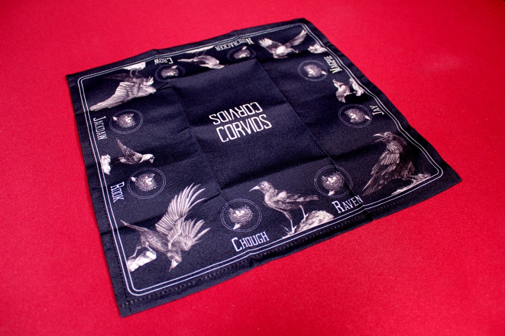 Game mat featuring various types of crows and the game title 'Corvids' displayed in a centered design.