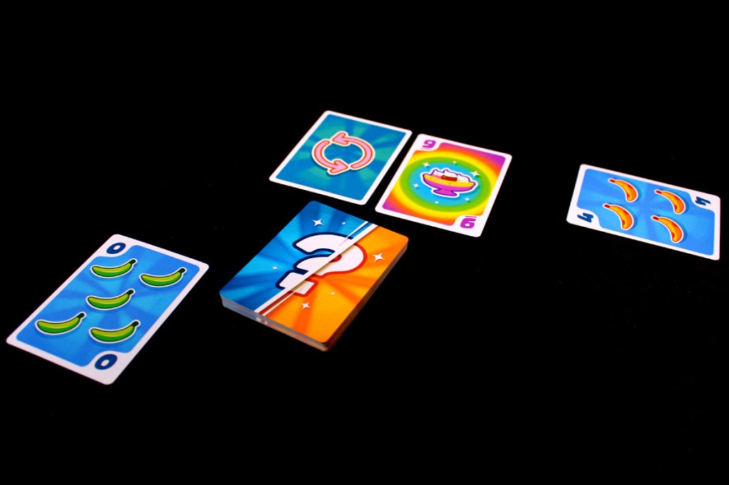 Colorful game cards from the board game Fifty Fruity, showing banana graphics and scores, arranged on a black background.