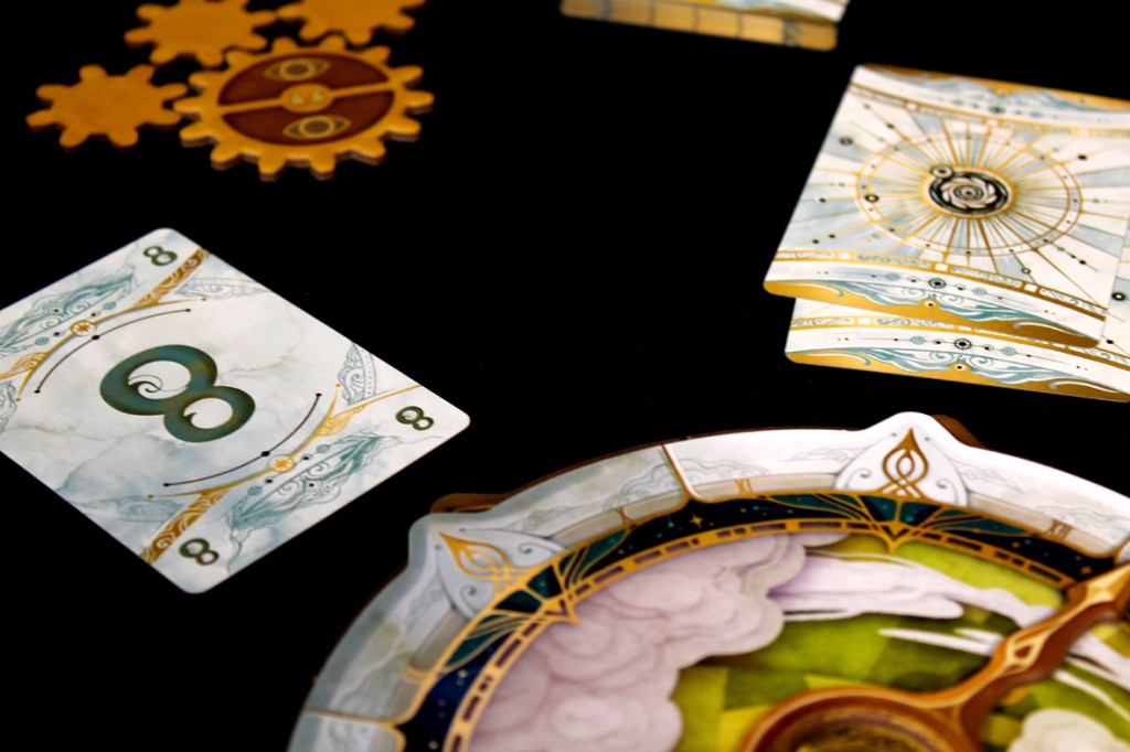 A close-up view of a game setup featuring an '8' card from a board game, decorative gear pieces, and a circular game board with intricate designs, all set against a black background.