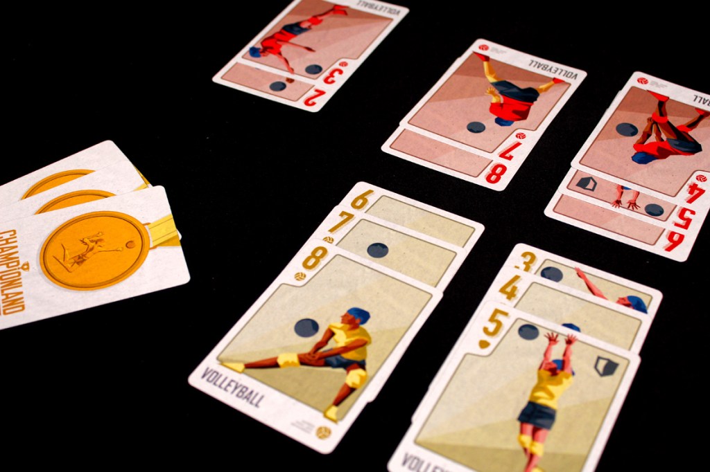 A close-up view of Championland: Volleyball game components, including cards showing volleyball players and a set of medals, arranged on a black surface.